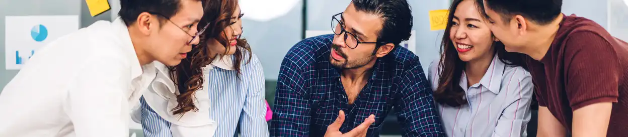 A teacher with glasses and a beard talking to students