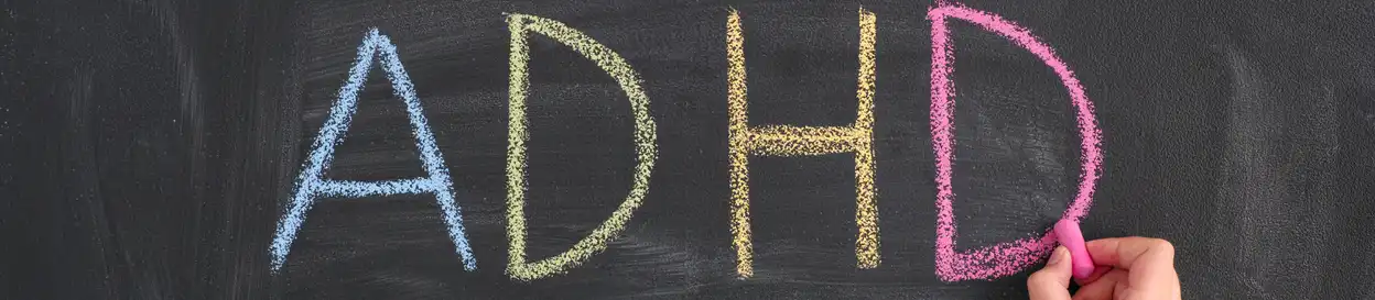 The letters ADHD (blue, green, yellow and pink) written on a chalkboard