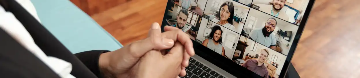 A teacher, with crossed hands, conducts a group lesson on a laptop