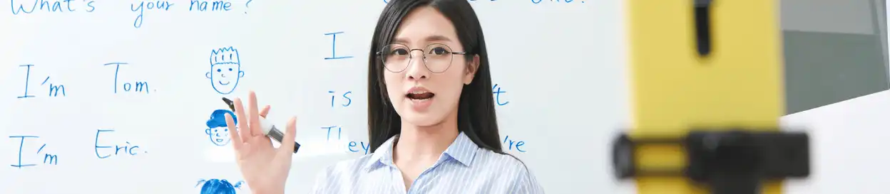 A woman standing in front of a whiteboard with English words on it 