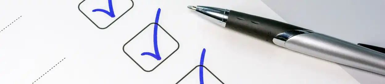 Checkmarks on a to-do list, a pen rests by the ticked boxes