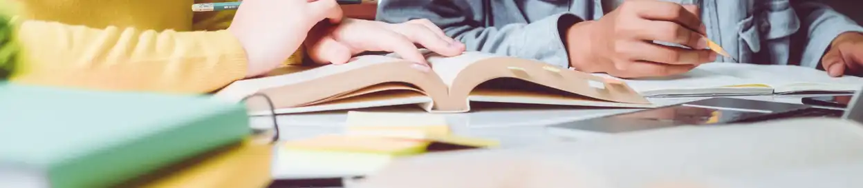 A teacher shows a student a page of a textbook