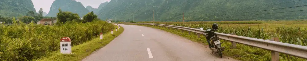 Photo of a road in Vietnam with a motorbike parked to the right