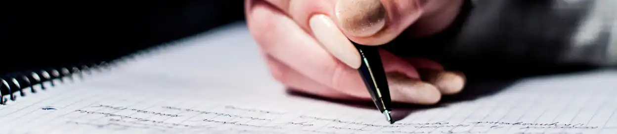 A hand, holding a pen, writing an essay