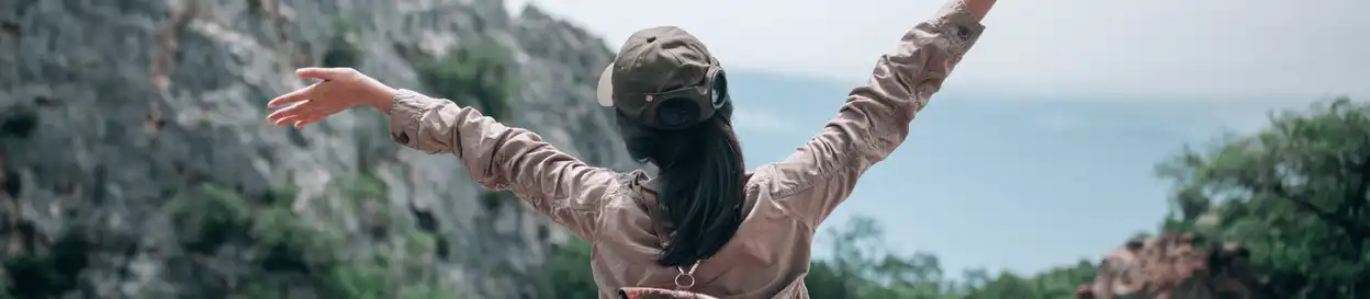 A woman with her arms up in front of a landscape