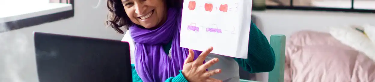 A teacher shows a book while conducting an online lesson