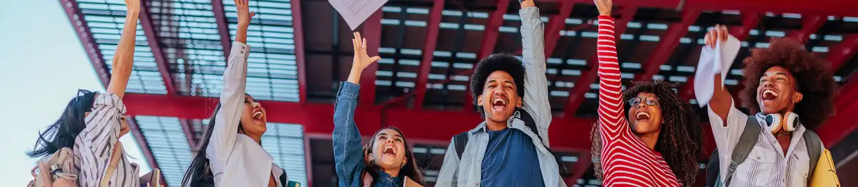 students celebrate passing an exam, throwing papers in the air
