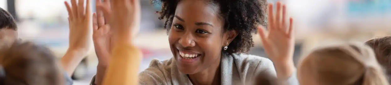 A smiling teacher receives high fives from her students