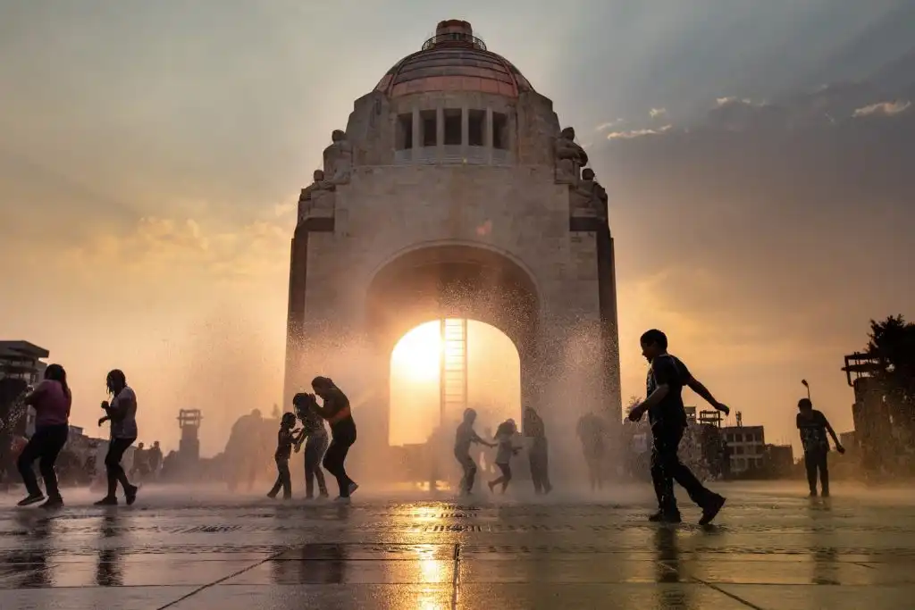 Children playing in the fountains at the Monumento a la Revolución in Mexico City at sunset