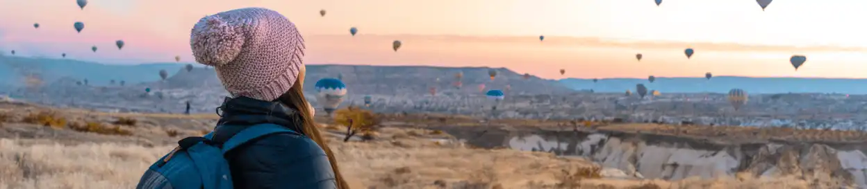 A woman looking at hot air balloons in the sky