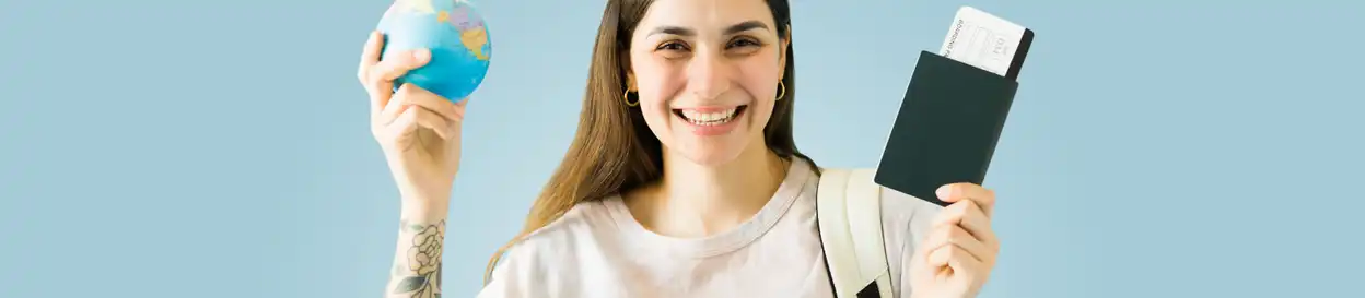 A woman holding up a small globe and passport