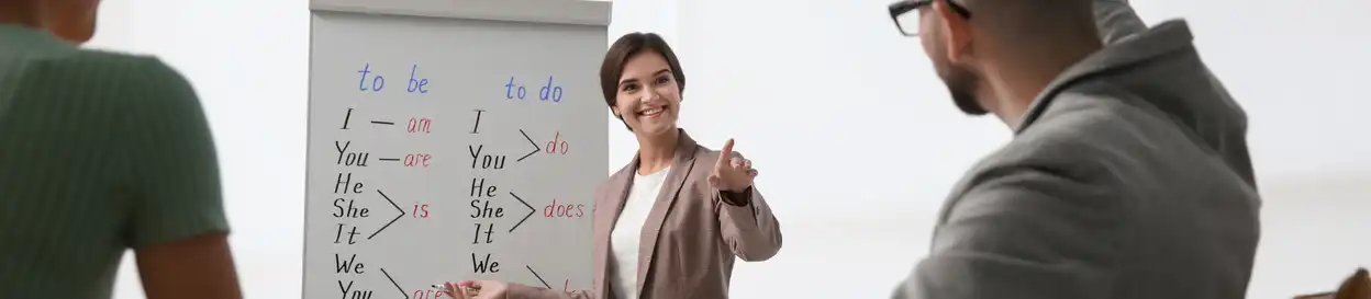 A woman pointing at a whiteboard with English phrases on it