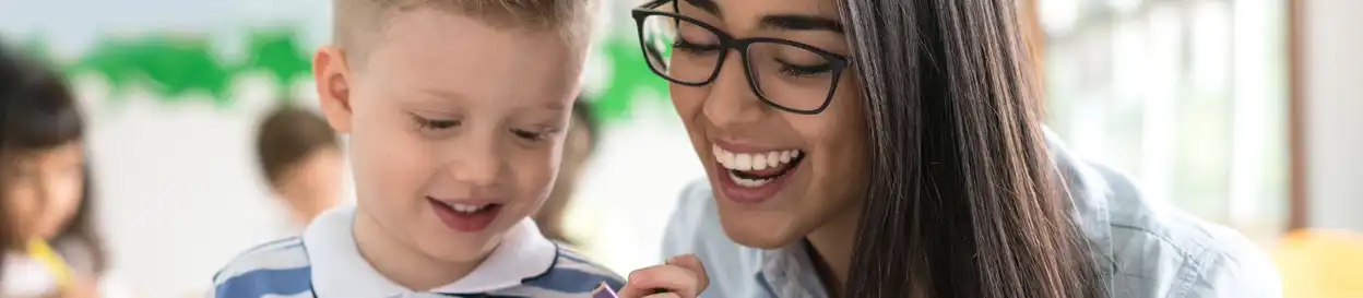 A female teacher helping a young boy in class