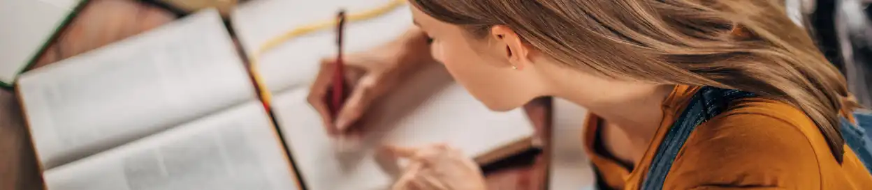 A woman studying and writing in a notebook