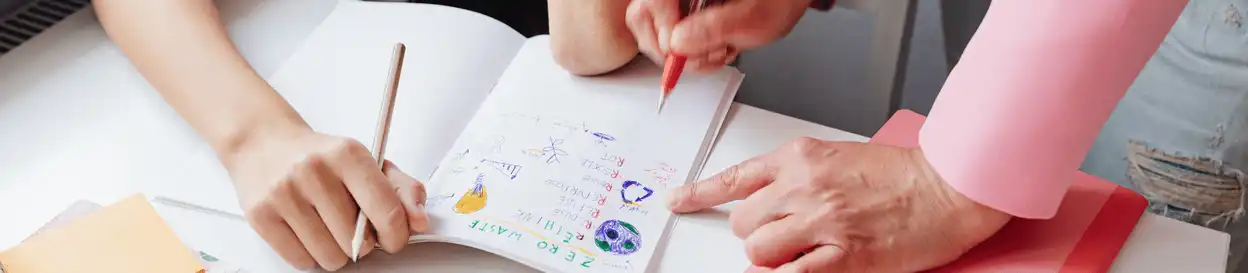 A young student and a teacher marking a school workbook