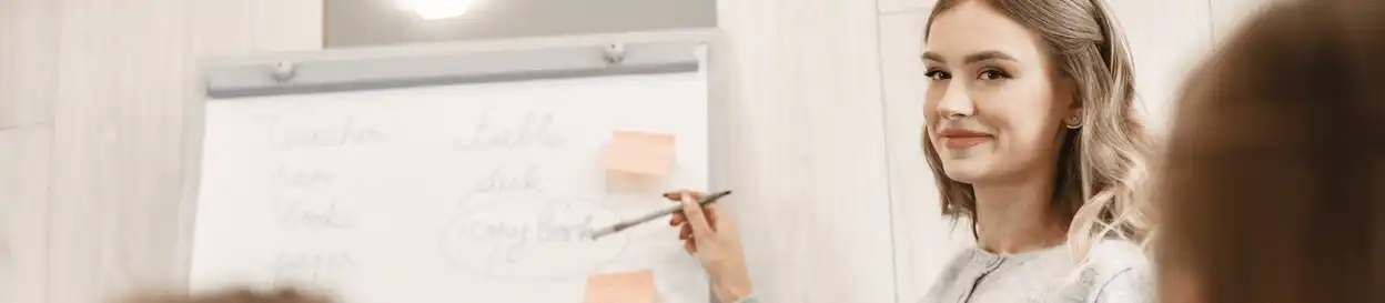 A woman pointing at a whiteboard with words written on it
