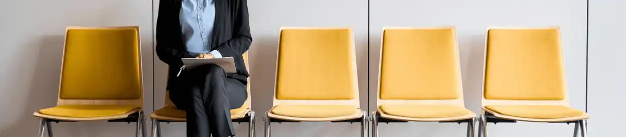 A woman waiting on a yellow chair for an interview