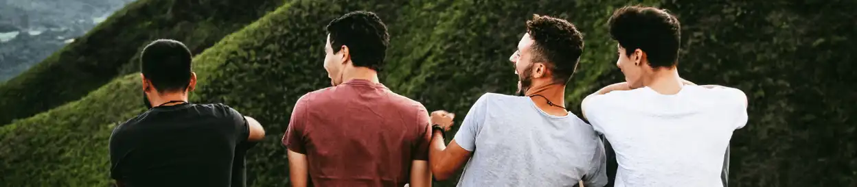 Four male friends sitting on a hill and laughing