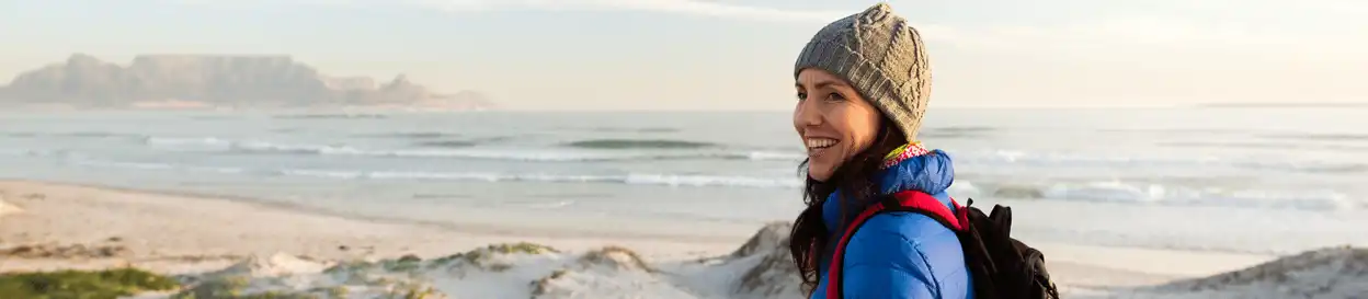 A woman in a woolly hat at a beach