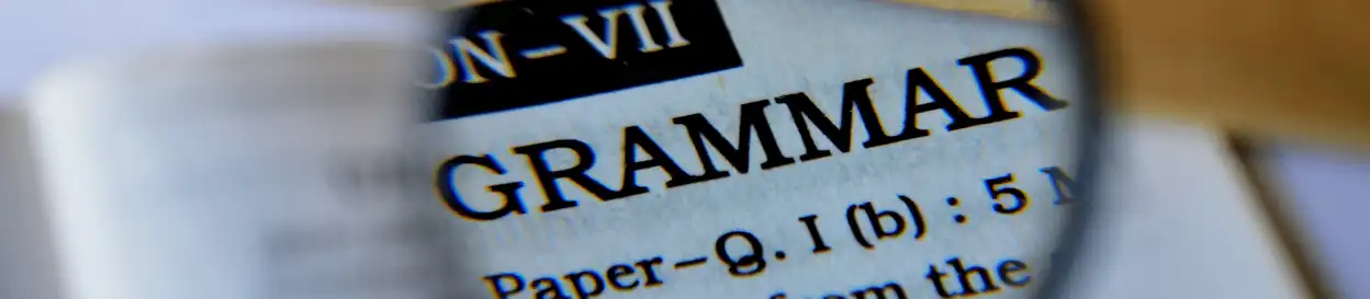 A magnifying glass magnifying the word 'grammar' in a book