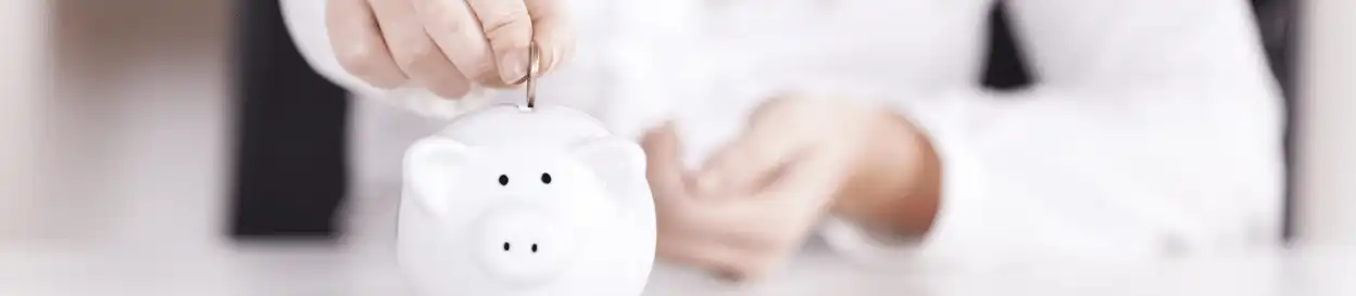 A woman adding a coin to a piggy bank