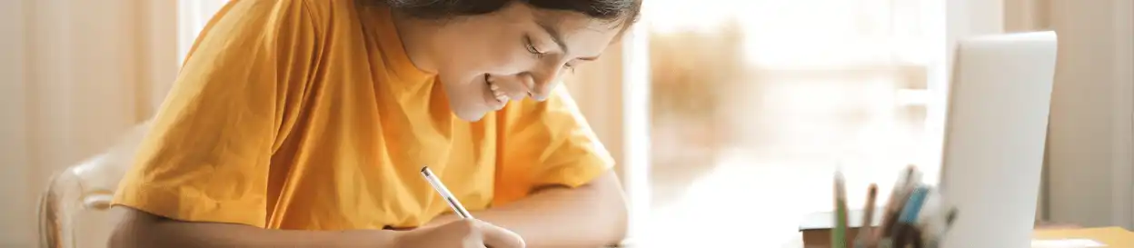 A woman in a yellow tshirt studying in front of a laptop