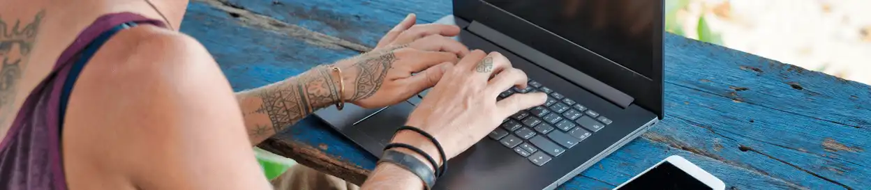 A woman with tattoos working on a laptop