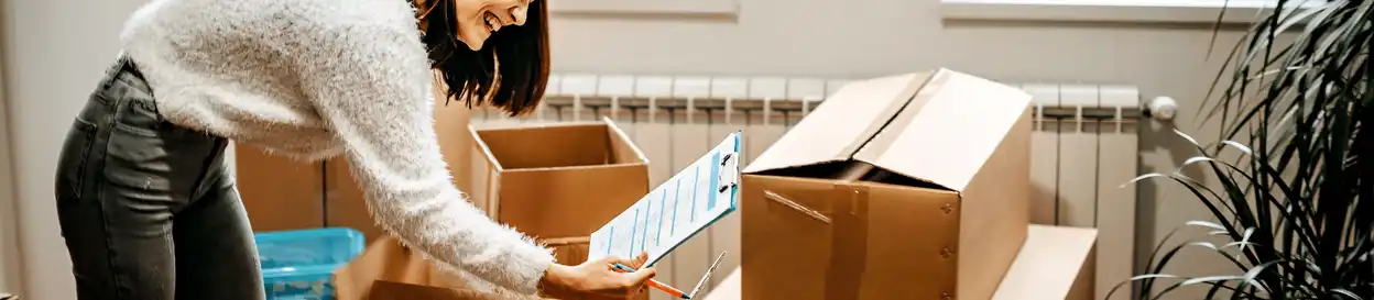 A woman packing boxes and looking at a checklist