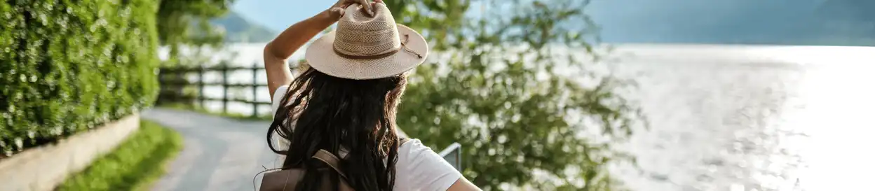 A woman wearing a hat looking out on a body of water