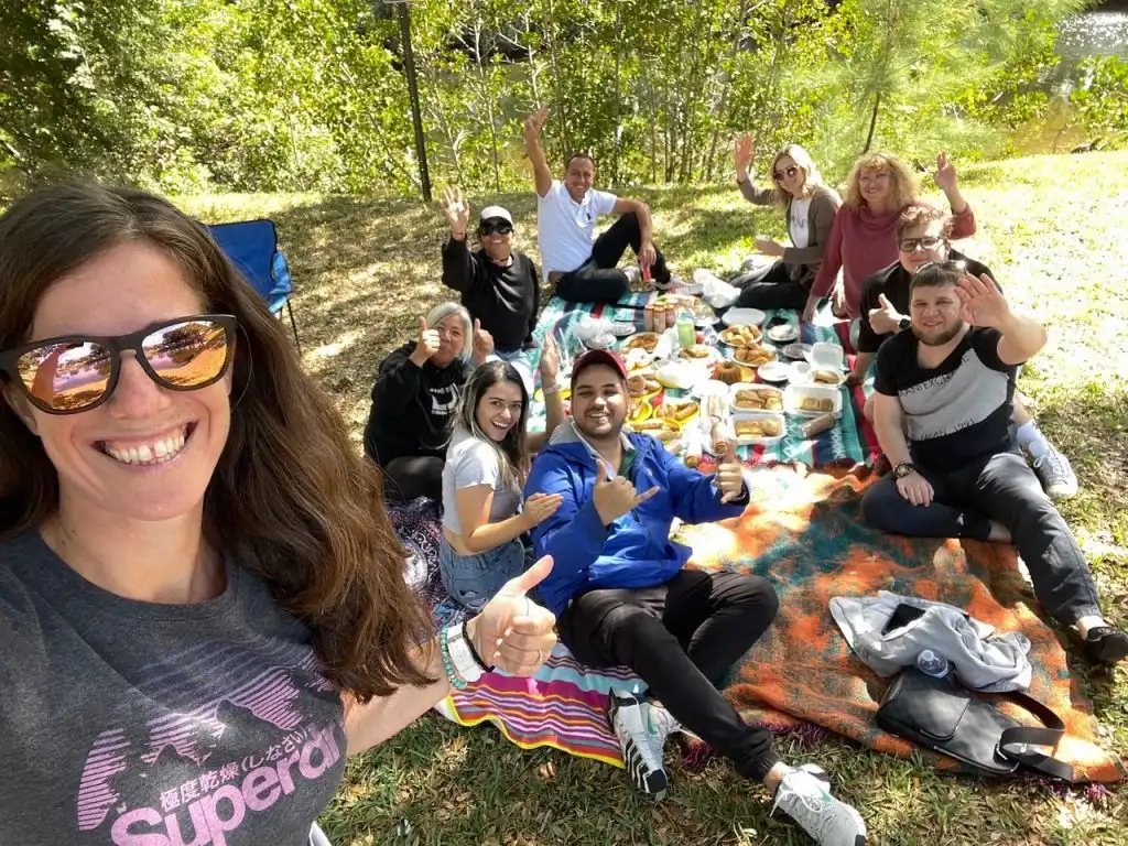Andrea smiling in front of a group of people having a picnic